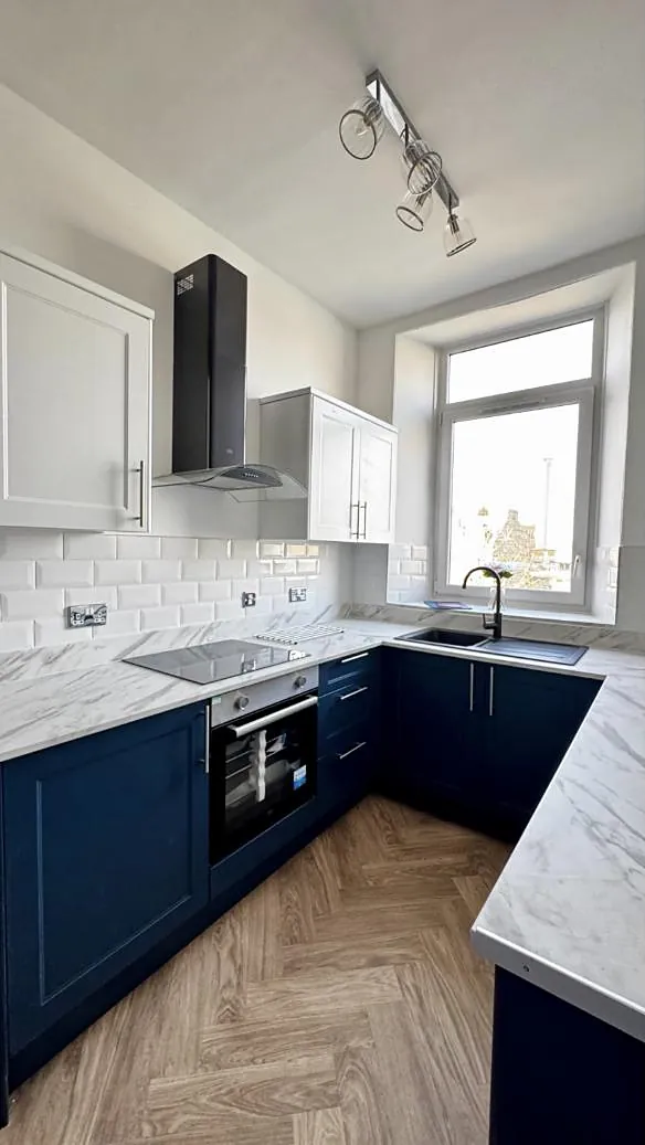 Navy shaker kitchen with marble-effect worktops and a herringbone floor