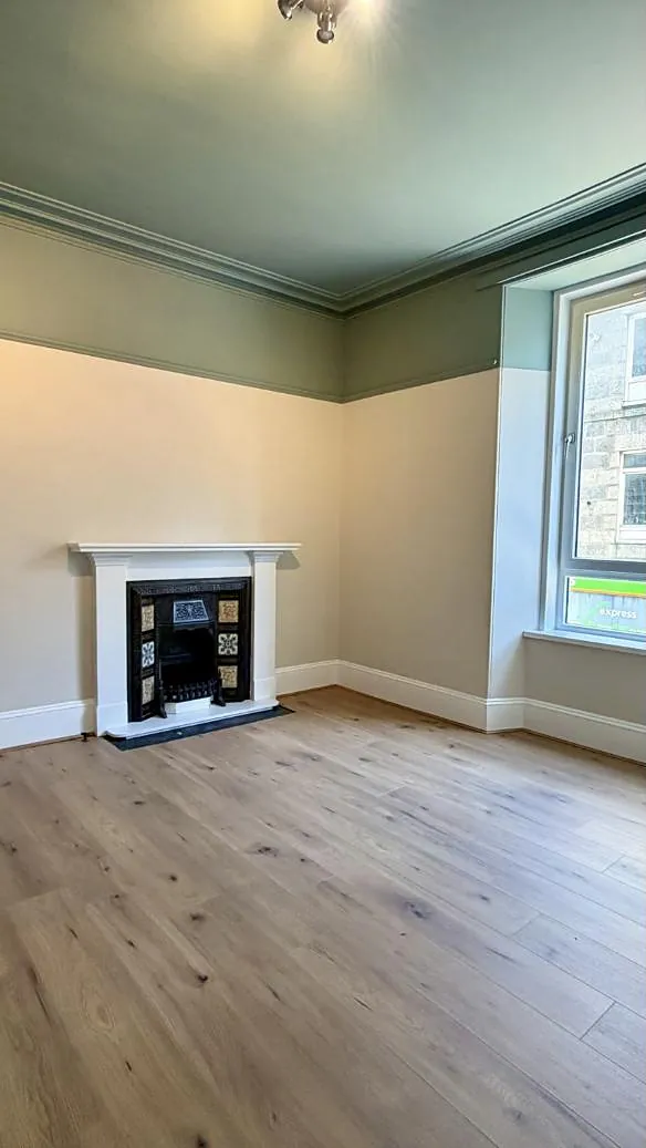 Bright room with a restored Victorian tiled fireplace and green cornicing