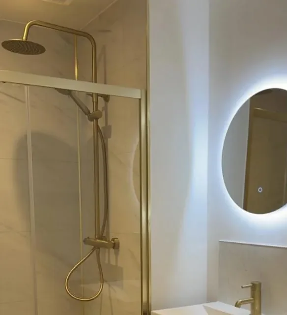 Holburn Street bathroom with a brushed brass rainfall shower, fluted vanity and round LED mirror